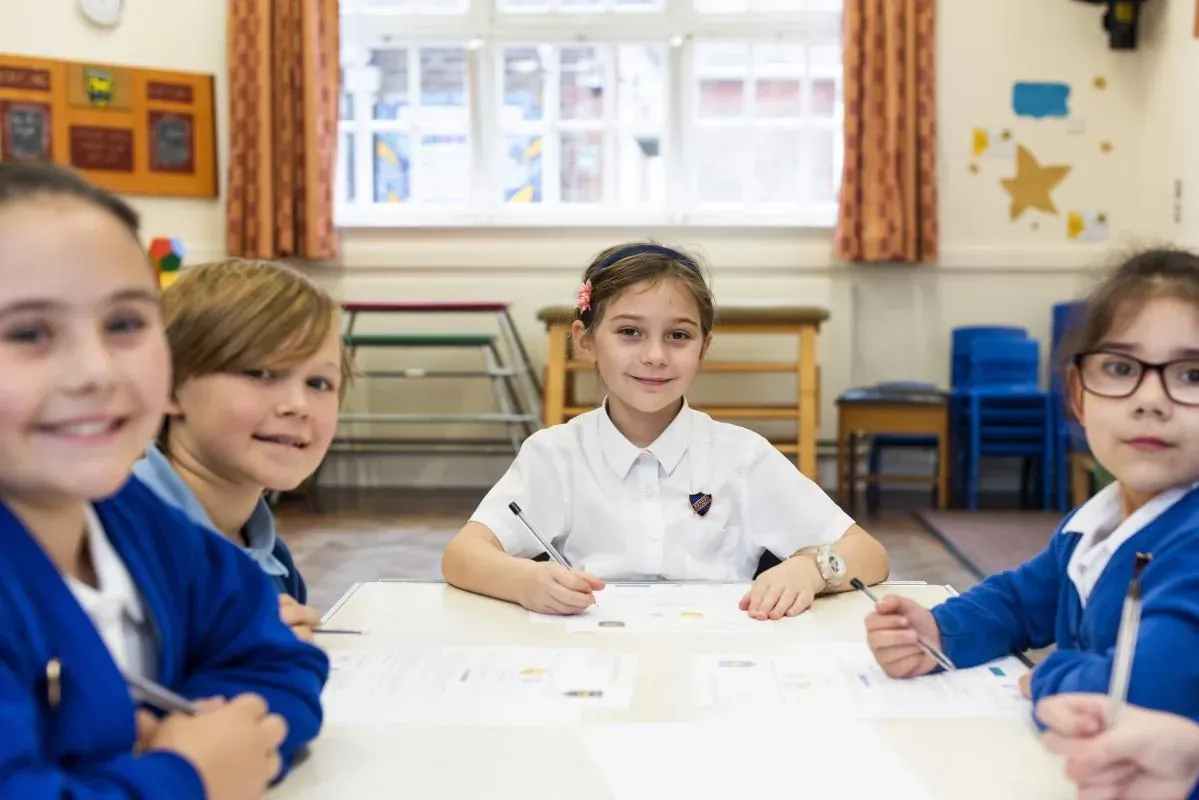 Four pupils smiling at a classroom table