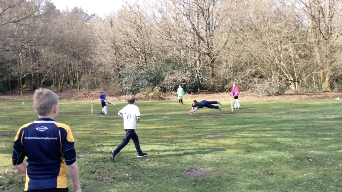Children playing football on the village sports ground surrounded by trees