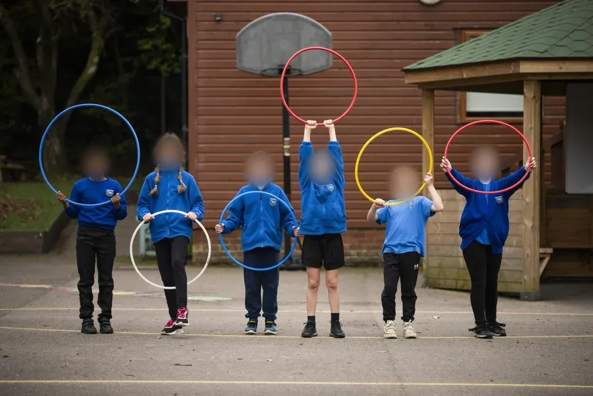 Children holding up colourful hoops in the school playground