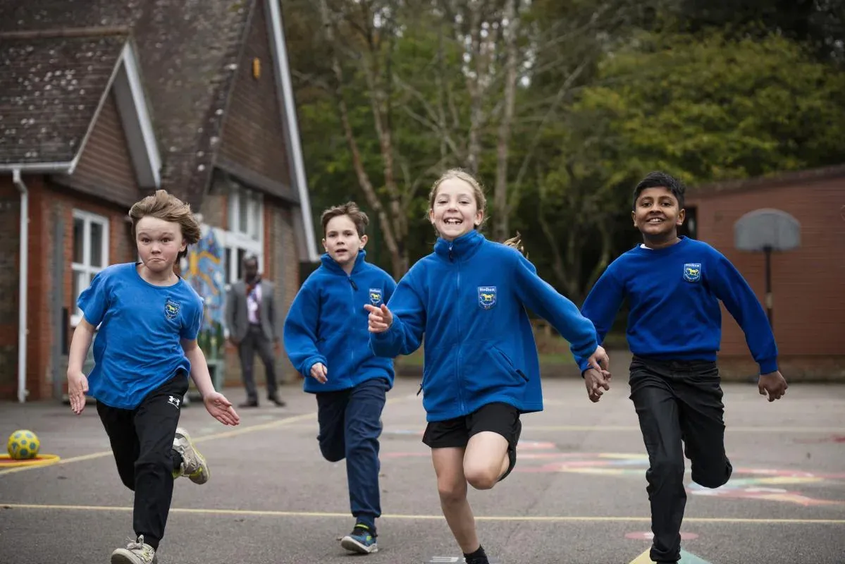 Children in blue fleeces running happily across the playground