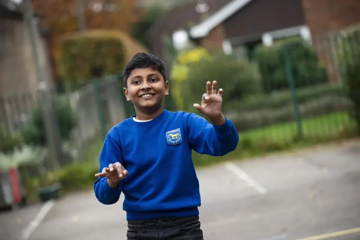 A smiling boy in a blue school fleece in the playground