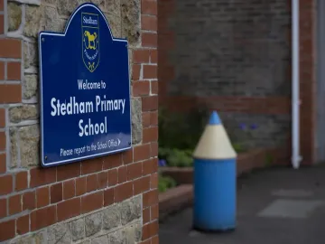 The blue Welcome to Stedham Primary School sign by the entrance